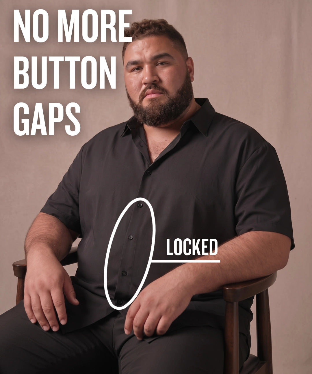 White man sitting on a chair wearing a black short-sleeve dress shirt, pointing at the button placket to show no button gap, front view