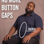 Black man sitting on a chair wearing a navy short-sleeve dress shirt, pointing at the button placket to show no button gap, front view