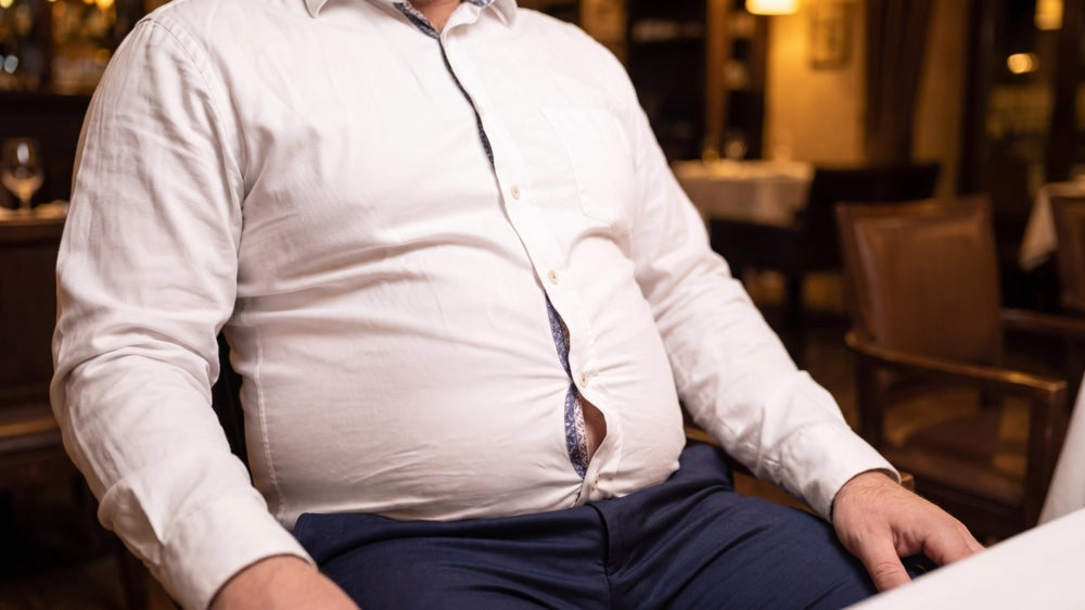 Close-up of a men's dress shirt gapping between buttons at the stomach, exposing the patterned inner placket lining underneath