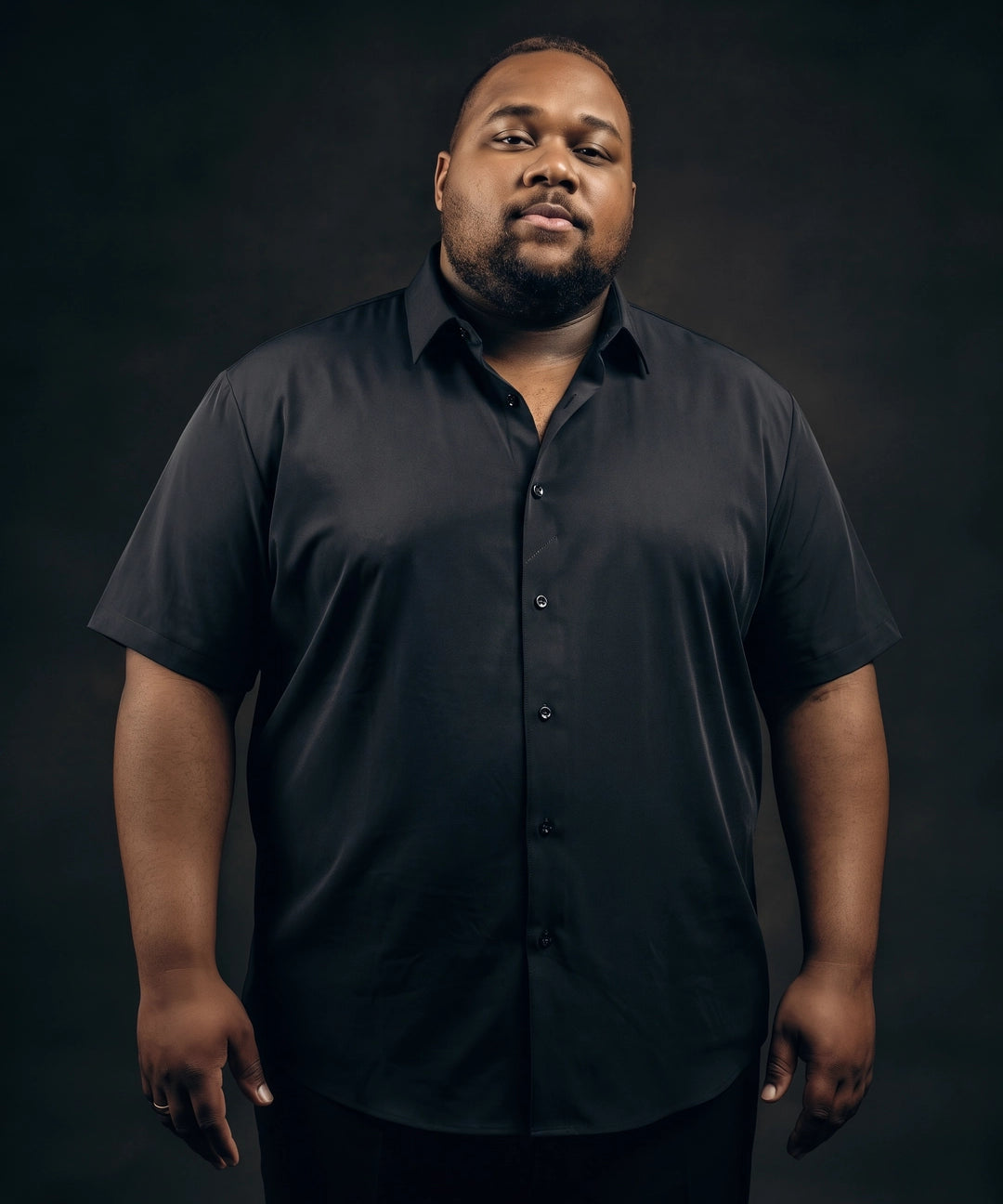Plus-size Black man trying on NEVER GAPE No-Gap Stretch Dress Shirt in Black, Short Sleeve, front view