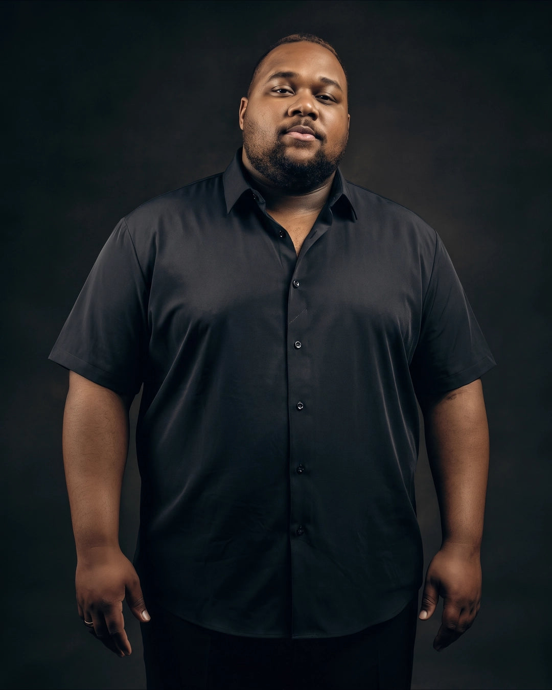Plus-size Black man trying on NEVER GAPE No-Gap Stretch Dress Shirt in Black, Short Sleeve, front view