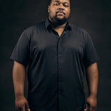 Plus-size Black man trying on NEVER GAPE No-Gap Stretch Dress Shirt in Black, Short Sleeve, front view