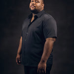 Plus-size Black man trying on NEVER GAPE No-Gap Stretch Dress Shirt in Black, Short Sleeve, side view