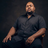 Plus-size Black man sitting in a chair wearing NEVER GAPE No-Gap Stretch Dress Shirt in Black, Short Sleeve