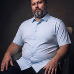 Plus-size white man sitting in a chair wearing NEVER GAPE No-Gap Stretch Dress Shirt in Light Blue, Short Sleeve