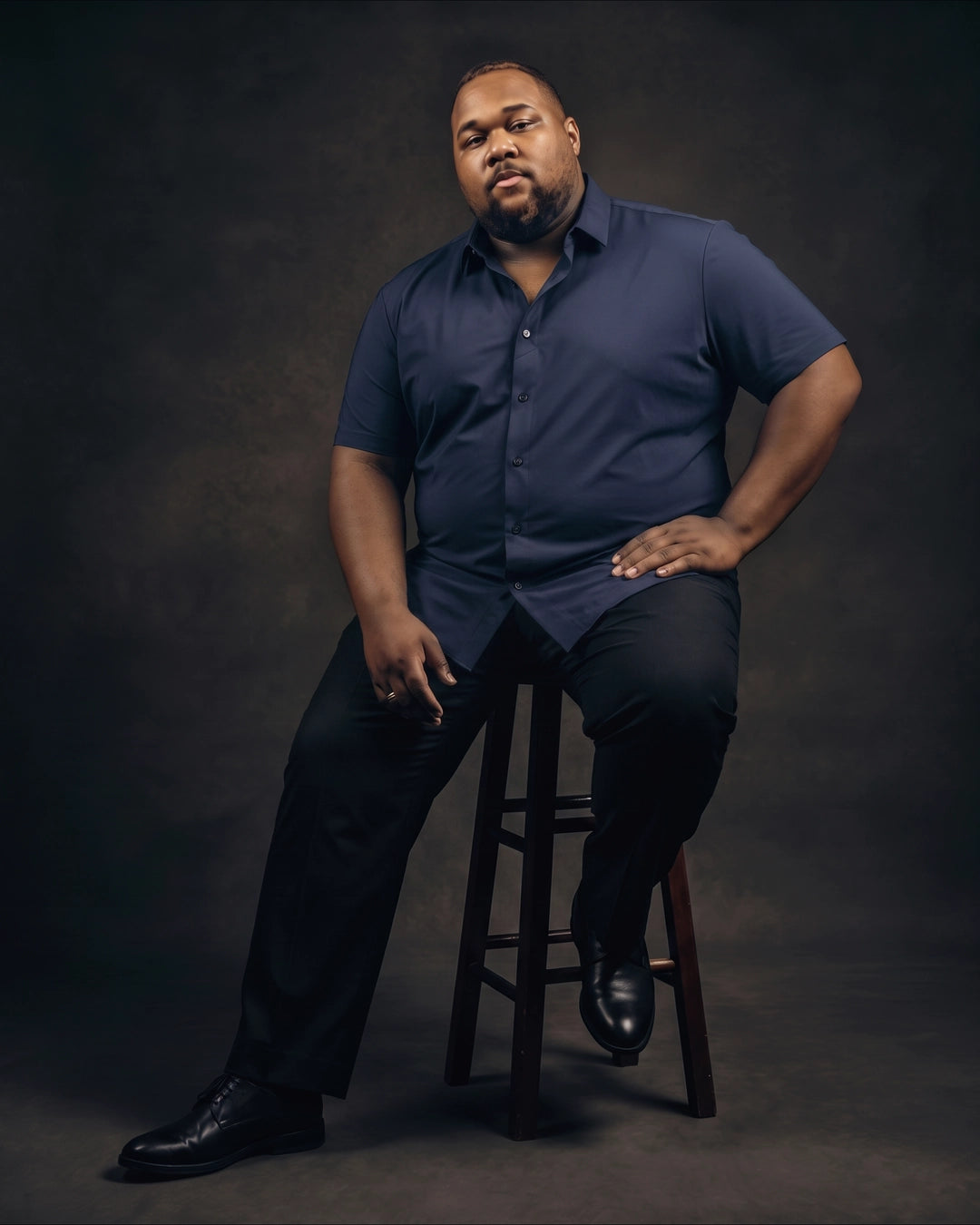 Plus-size Black man sitting in a chair wearing NEVER GAPE No-Gap Stretch Dress Shirt in Navy, Short Sleeve