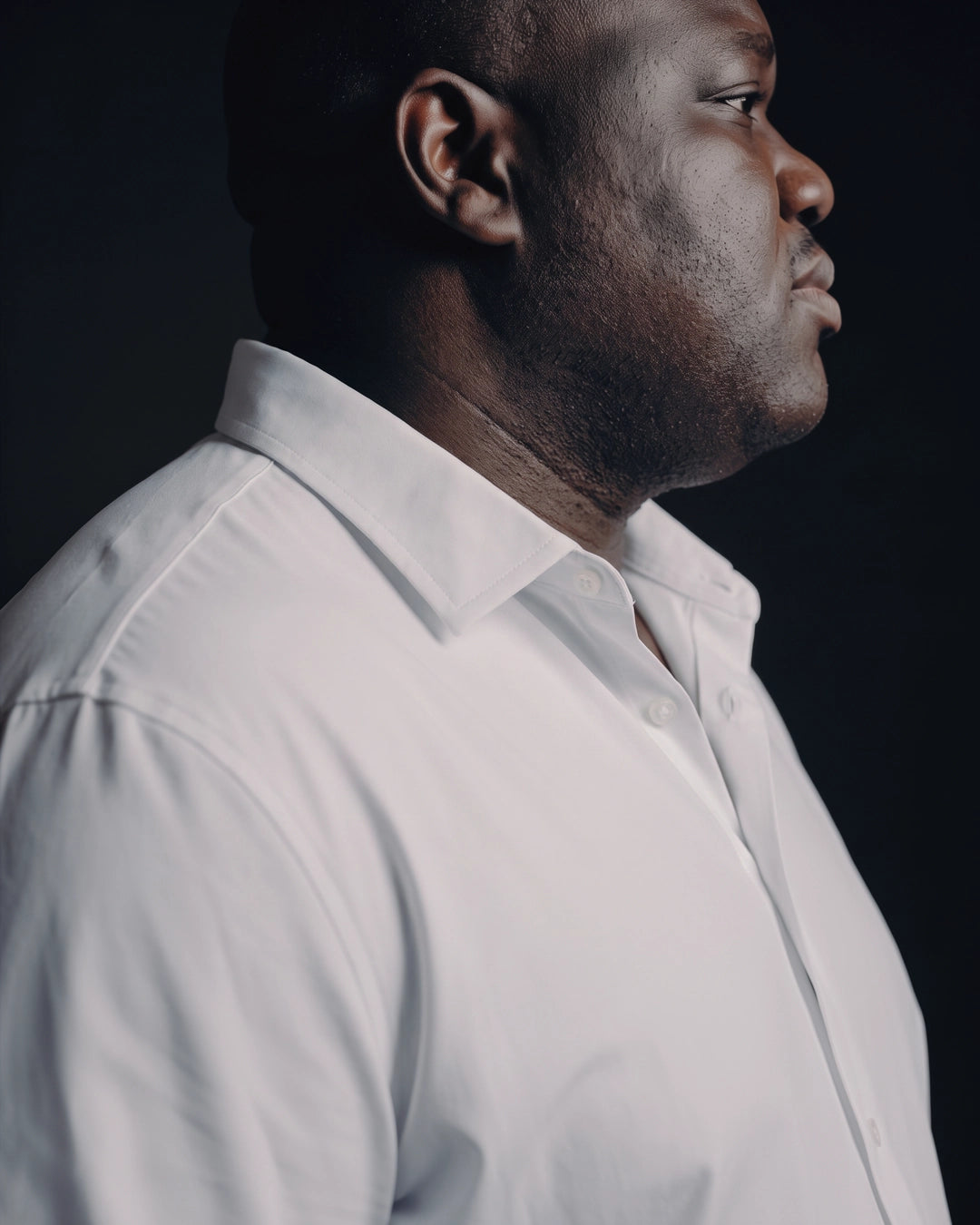 Plus-size Black man trying on NEVER GAPE No-Gap Stretch Dress Shirt in White, Long Sleeve, side view