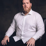 Plus-size white man sitting in a chair wearing NEVER GAPE No-Gap Stretch Dress Shirt in White, Long Sleeve