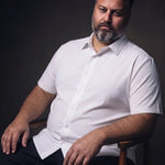 Plus-size white man sitting in a chair wearing NEVER GAPE No-Gap Stretch Dress Shirt in White, Short Sleeve